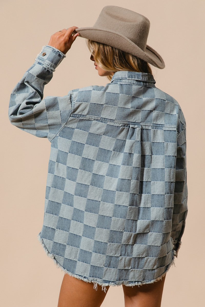 Person wearing a checkered denim shirt and hat on a beige background