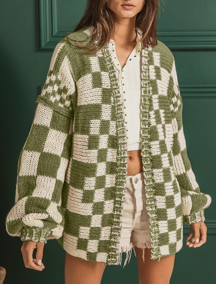Woman wearing a green and white checkered cardigan against a green wall.