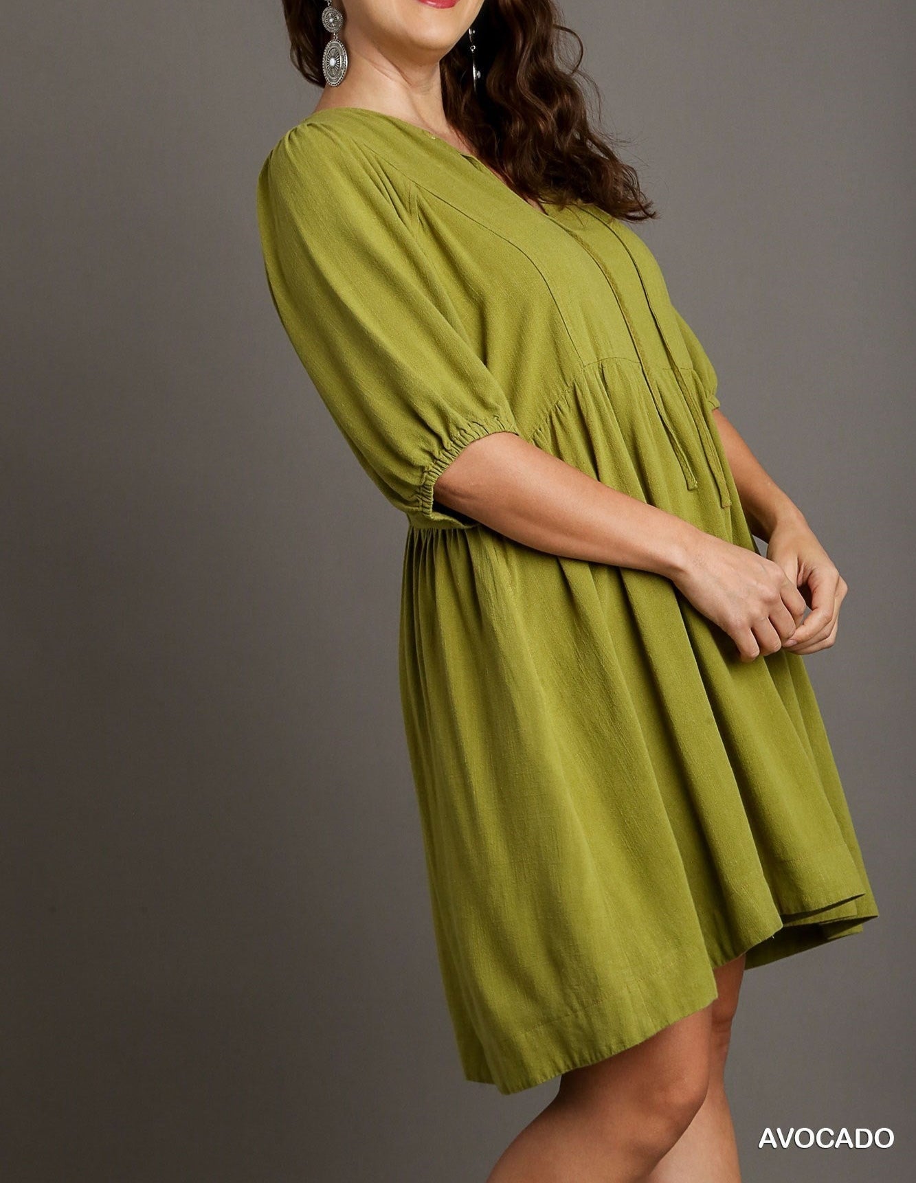 Woman wearing a green plus-size dress on a gray background