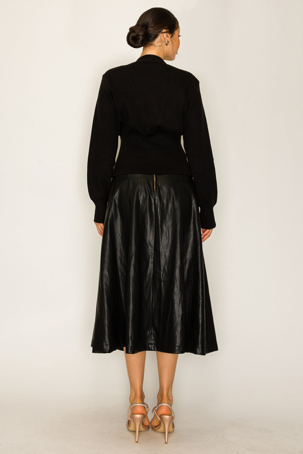 Person wearing a black outfit with a leather skirt on a white background