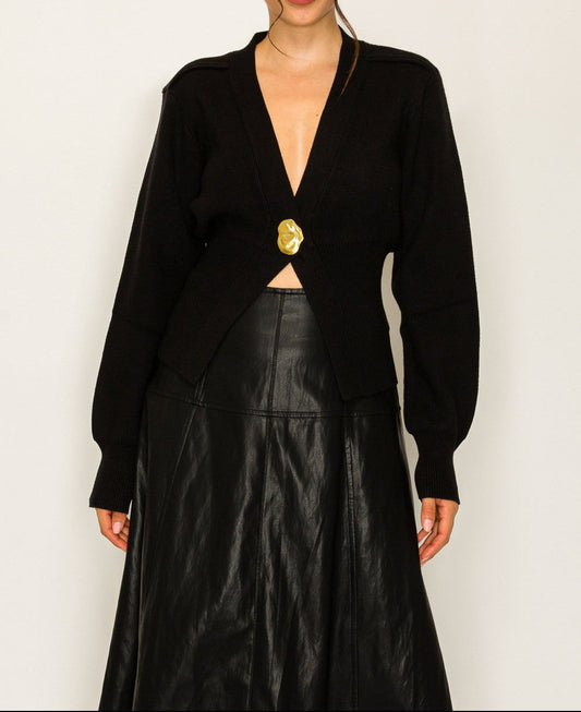 Woman wearing a black blazer with a gold button and black leather skirt on a white background