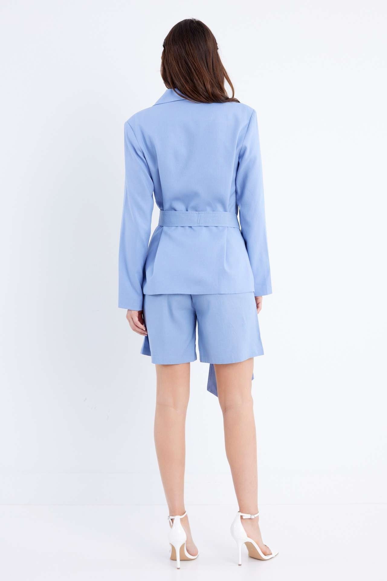 Woman wearing a light blue suit with a jacket and shorts on a white background