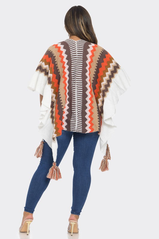 Woman wearing a patterned poncho with tassels on a white background