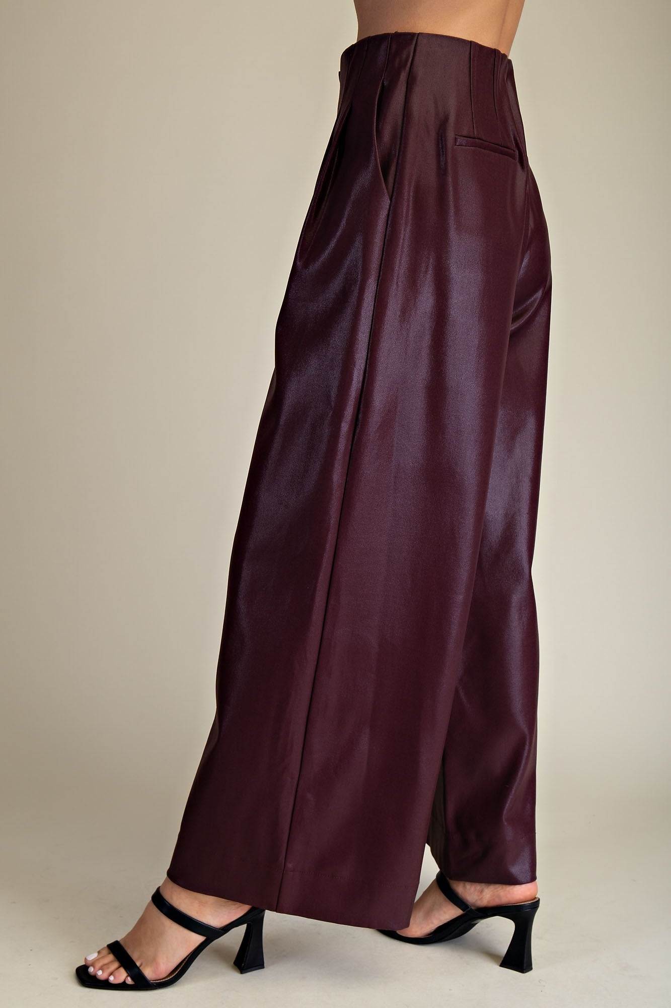 Maroon faux leather pants worn by a person on a neutral background