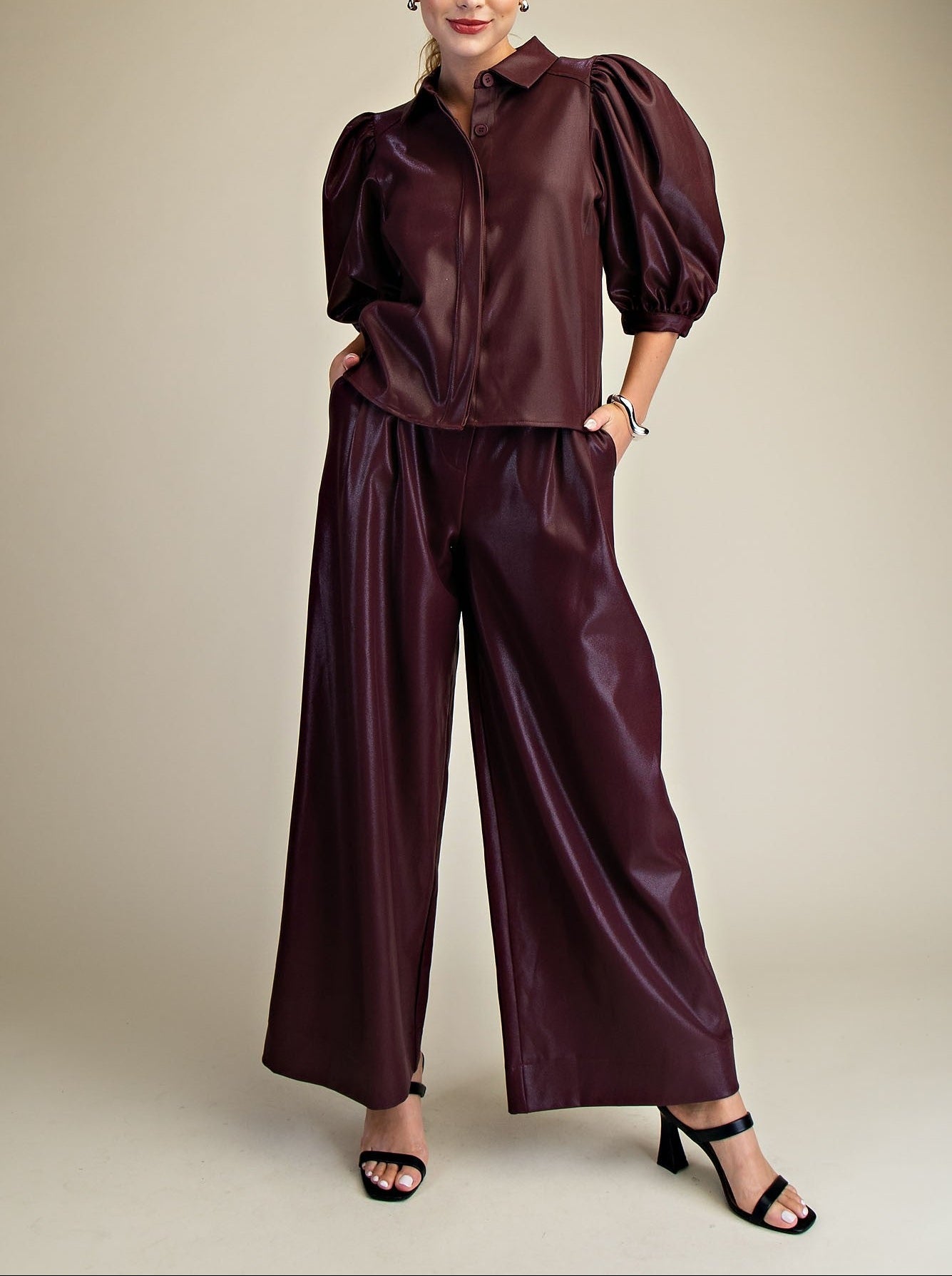 Woman wearing a maroon faux leather outfit on a beige background