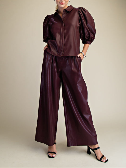 Woman wearing a maroon faux leather outfit on a beige background