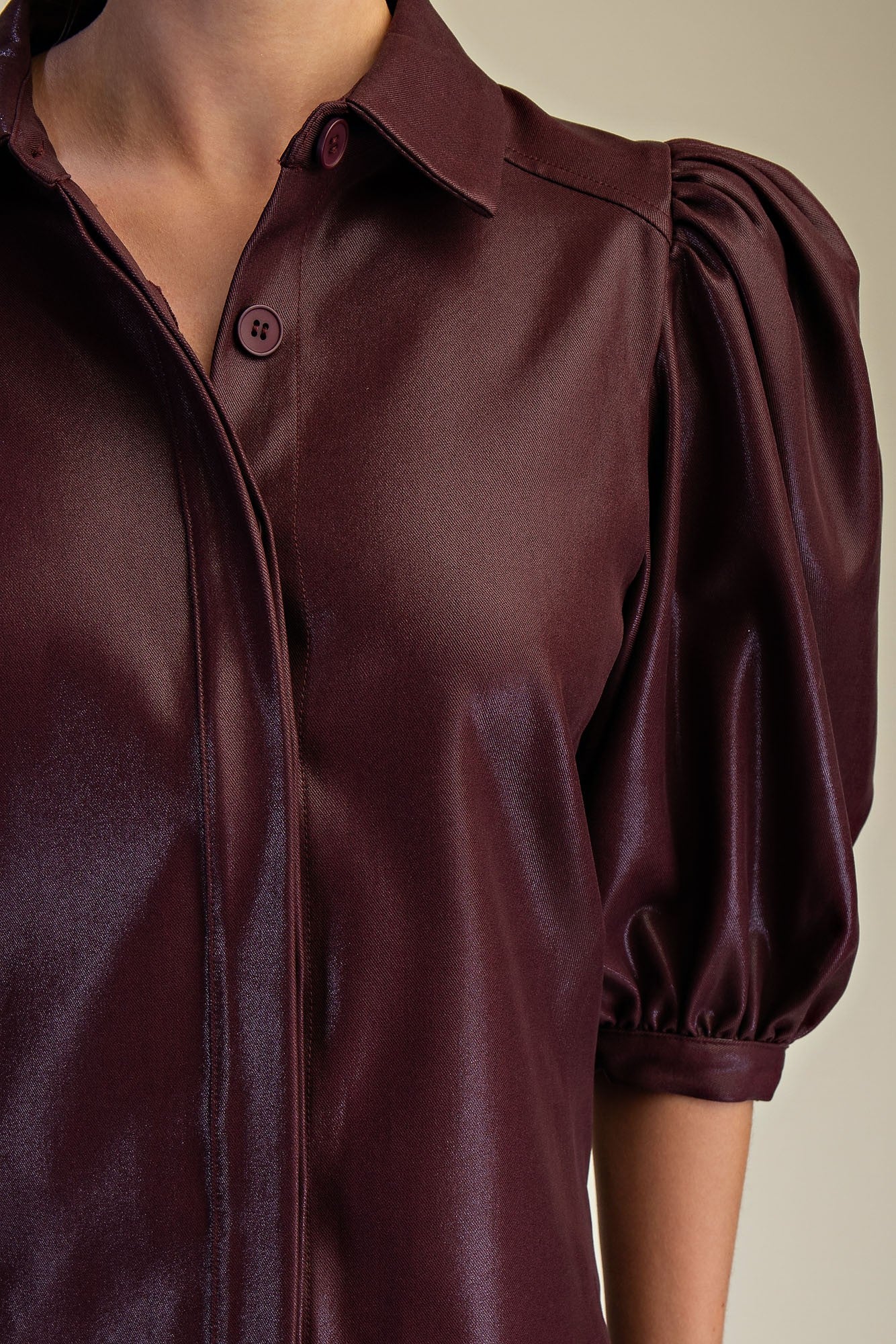 Close-up of a burgundy blouse with puffed sleeves on a neutral background