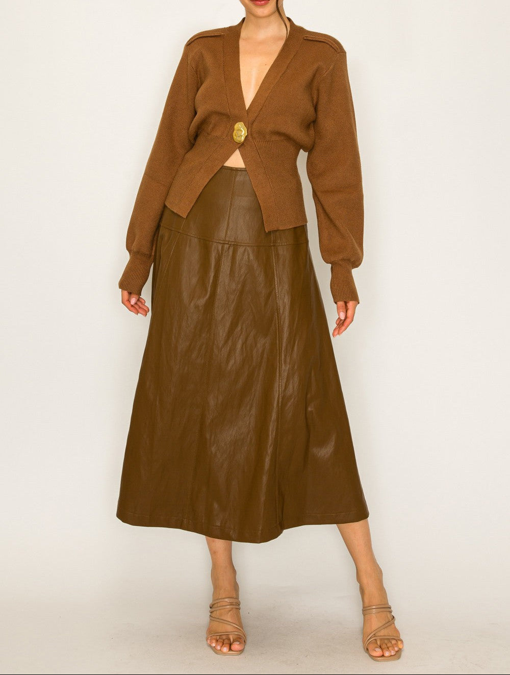 Woman wearing a brown outfit with a leather skirt on a white background