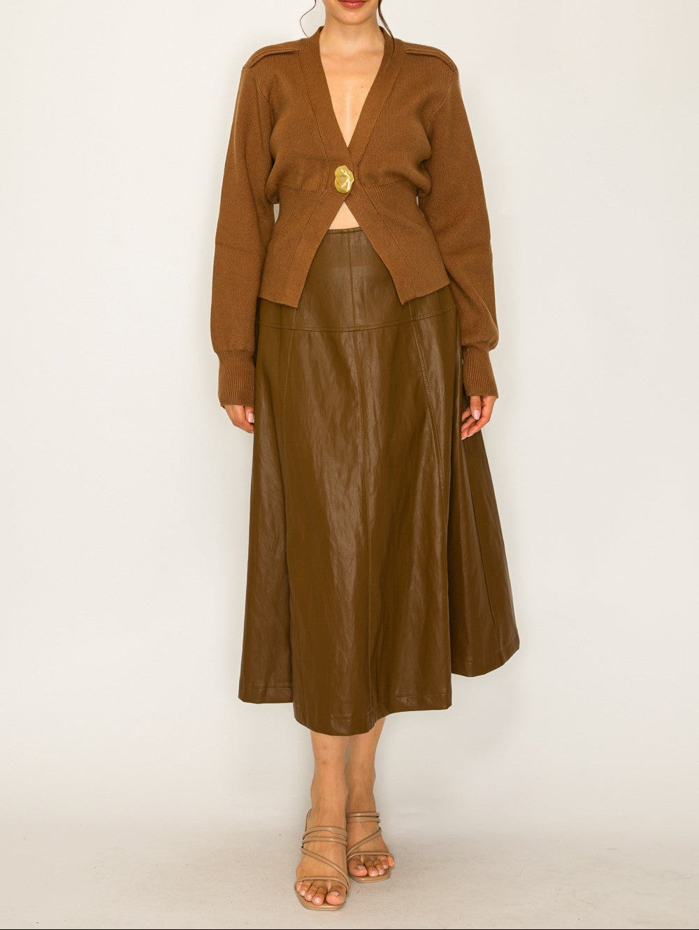 Woman wearing a brown outfit with a jacket and leather skirt on a white background
