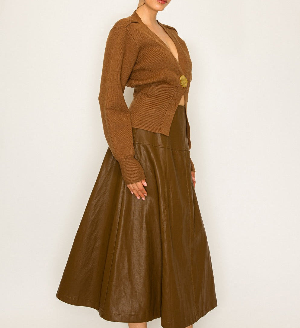 Woman wearing a brown cropped cardigan and leather skirt against a white background