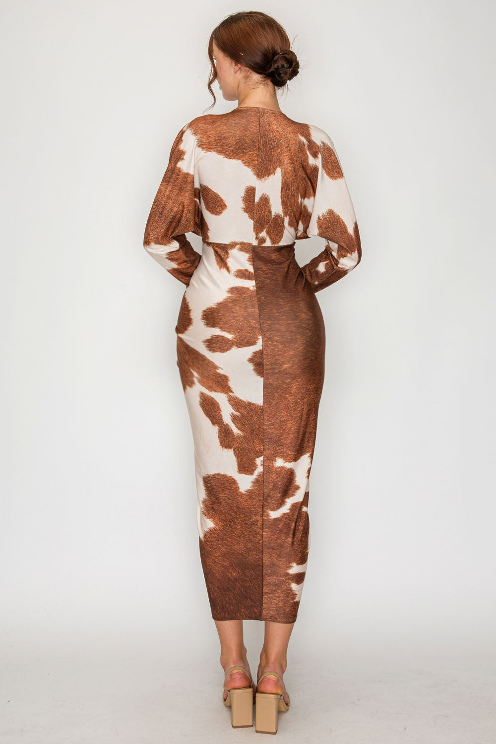Woman wearing a cow print dress on a white background
