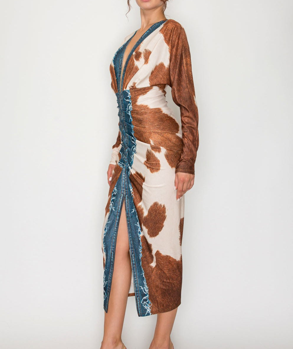 Woman wearing a cow print dress with denim accents on a white background