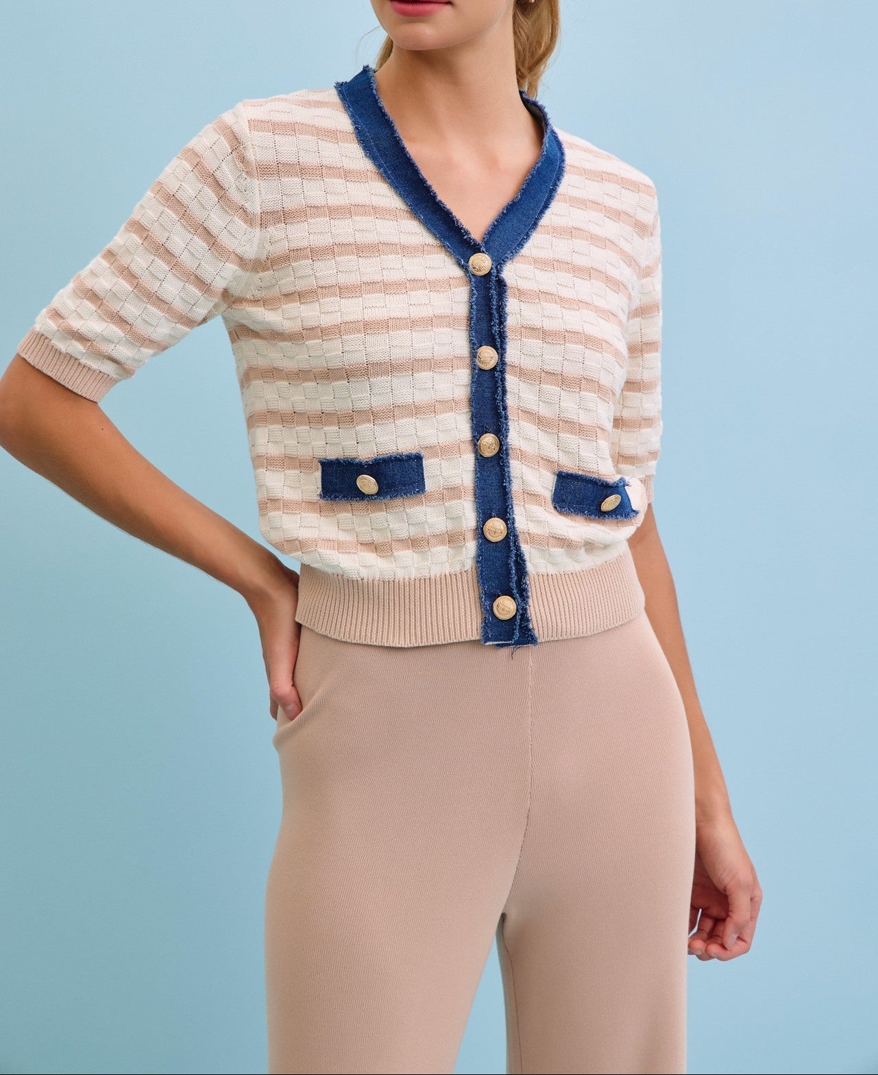Woman wearing a striped cardigan with blue accents on a light blue background