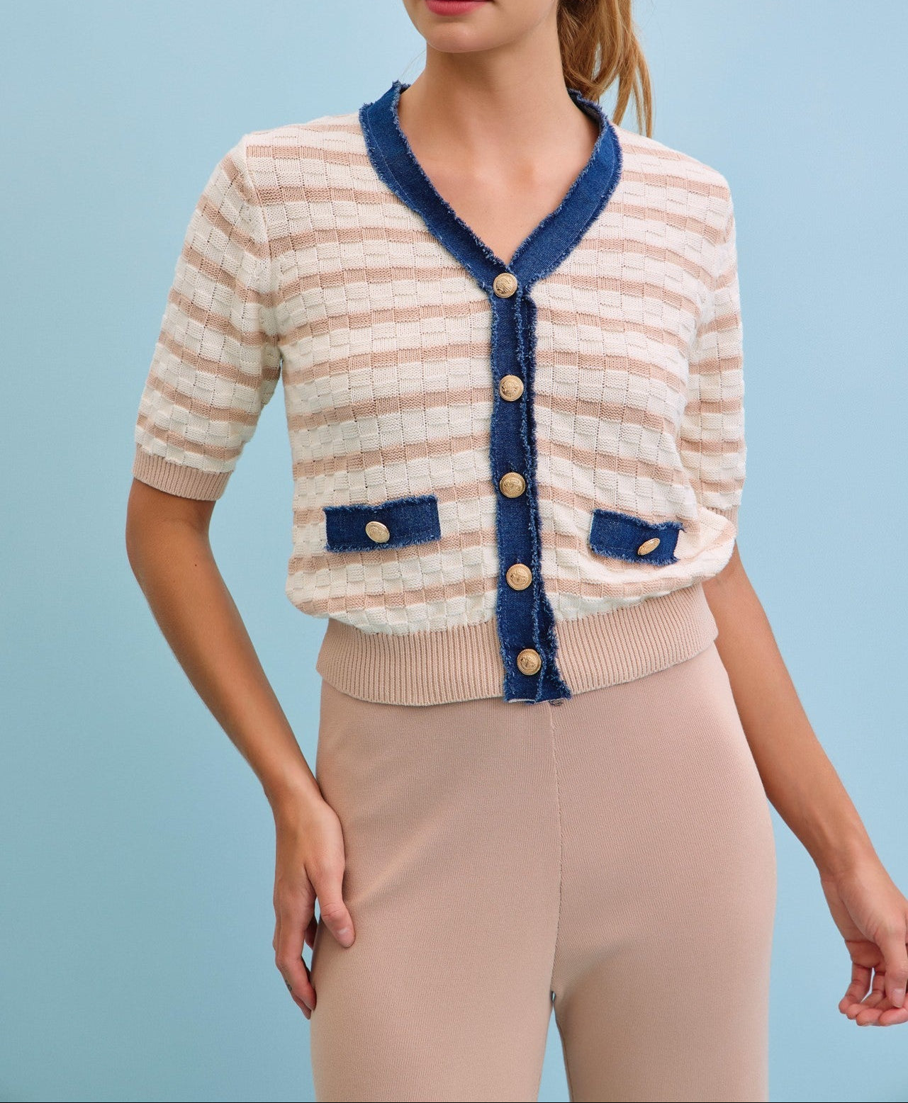 Woman wearing a striped cardigan with blue accents on a light blue background