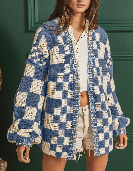 Woman wearing a blue and white checkered cardigan against a green wall.