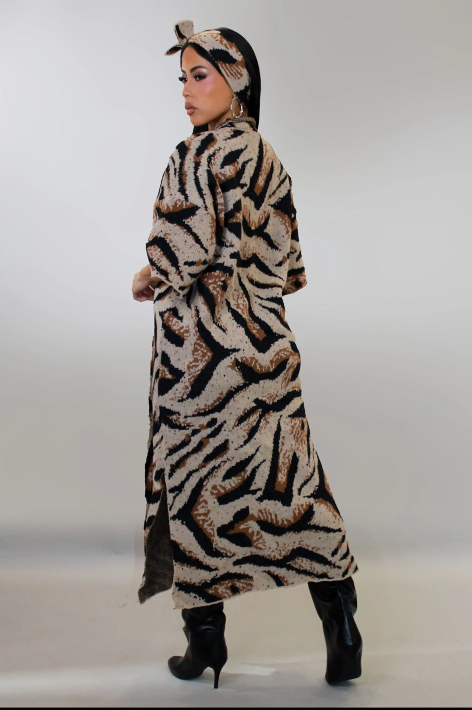 Person wearing a long tiger-striped coat with a hood on a white background