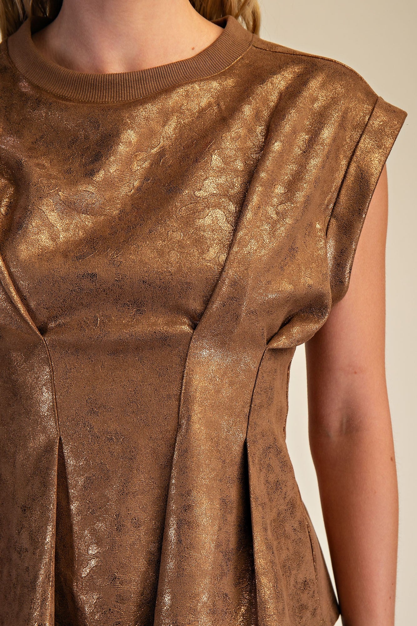 Close-up of a person wearing a bronze metallic dress against a neutral background