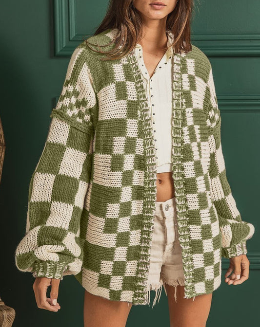Woman wearing a green and white checkered cardigan against a green wall.
