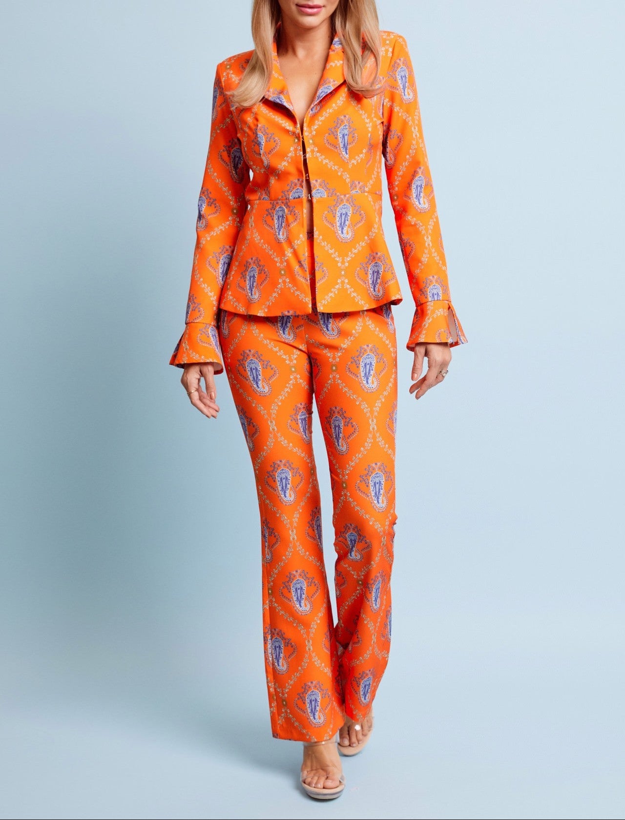 Woman wearing an orange patterned outfit on a light blue background